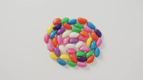 Video of overhead view of multi coloured sweets forming circle over white background