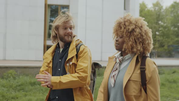 Multiethnic Man and Woman Walking in City and Chatting