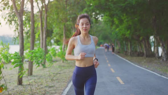 Asian young beautiful woman athlete running for health in evening sunset on street in public park.