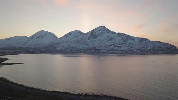 Sunset behind Kvaløya mountains in Tromvik, Tromsø. Northern Norway. Drone 4k. Push in towards the