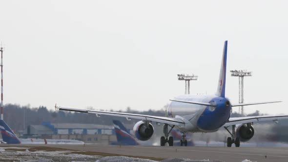 A Back View of a Plane Moving on an Airport Courtyard