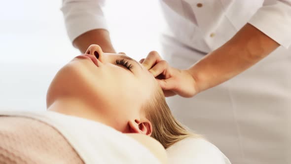 The beautician makes a relaxing massage for spasm of the muscles of the forehead of the face.