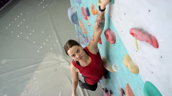 Young Caucasian Woman Hanging off Indoor Climbing Wall