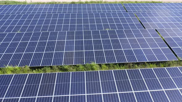 Drone Low Shot Over Rows of Angled Photovoltaic Solar Panels to Sunlight in Tropics,  Panning Left t