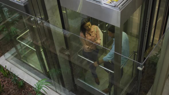 Video of diverse businesswoman and businessman talking in elevator