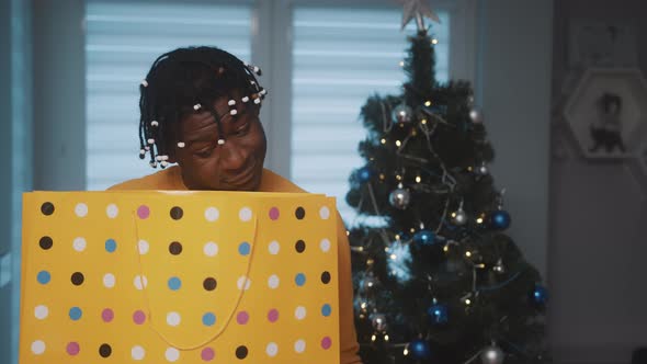 Shy and Inpatient African American Black Man Looking Into the Shopping Bag To See His Christmas Gift