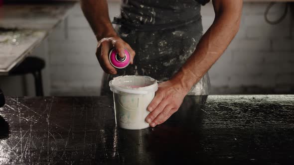 Man works with paint in his trowel. Mixes paint with polymer.