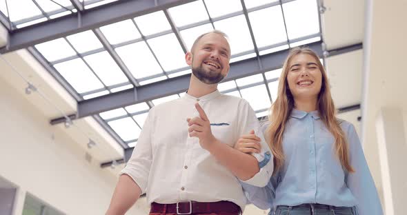 Beautiful Young Couple Walking and Talking on a Shopping Center Holding Hands