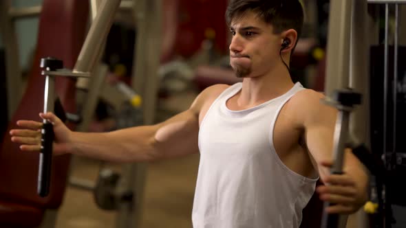 Extreme closeup of teen bodybuilder doing vertical deltoid fly exercises on a machine at a fitness g