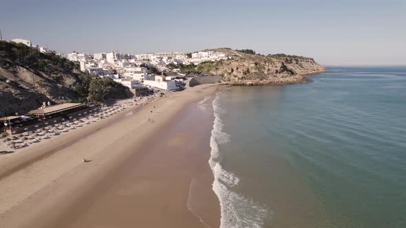 Breathtaking aerial view of Burgau Portugal splitting between aqua green ocean