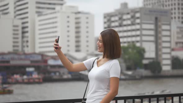 Tourist young Asian woman having video chat using smartphone connecting with friends.