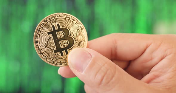 Hand Holding Bitcoin Over Green Background