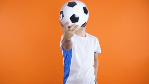 Confident Looking Football Fan or Player Posing with Football in Front of Face, Then Holding It