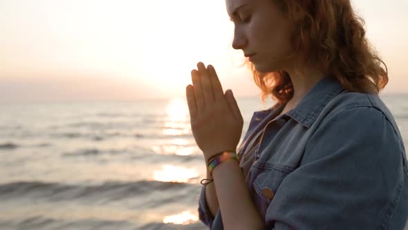 Young Lesbian LGBT Woman Prays for Equal Rights During Sunset at Sea