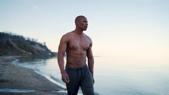 Attractive and muscular man walking along the shore in slow motion