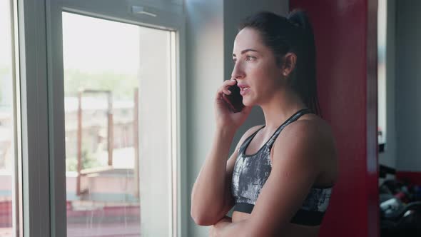 Portrait of Young Female Fitness Guru of Hair Tied in a Ponytail in a Suit for Fitness Talking on