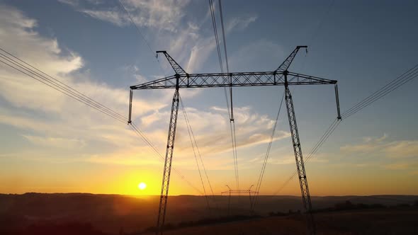 Dark Silhouette of High Voltage Tower with Electric Power Lines at Sunrise