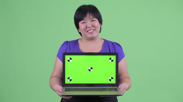 Happy Young Overweight Asian Woman Talking While Showing Laptop
