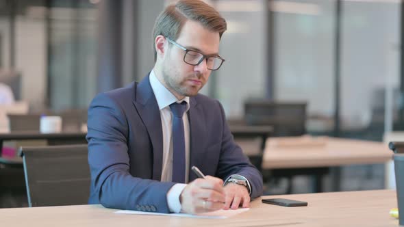 Pensive Businessman Writing on Paper, Thinking