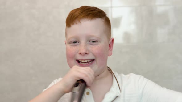 Little Boy is Shaving His Face with Electric Razor in the Bathroom