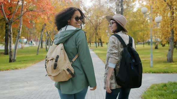 Slow Motion of Attractive Girls Friends Walking with Backpacks in City Park