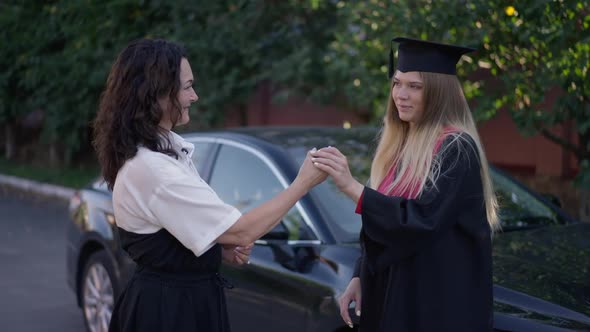 Happy Graduate Daughter Hugging Mother Giving Car Key in Slow Motion