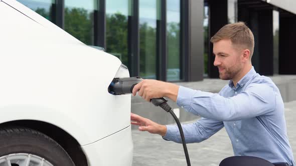 Close Up Man Inserting Power Cable Supply for Charging Electric Car