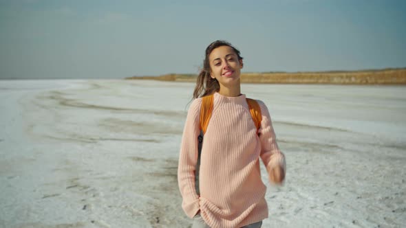 Cheerfulness Woman in Cozy Sweater with Orange Backpack on Nature Landscape of the Salt Flats Looks