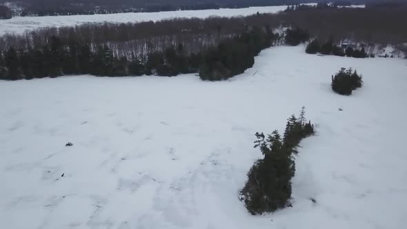 Aerial Drone View Flying Over Frozen Ice Lake Following Snowmobile Rider In Winter 1