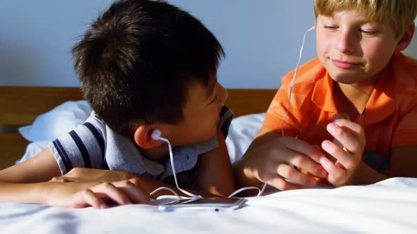 Siblings using mobile phone in bedroom