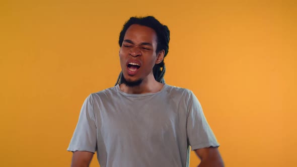 Bored African Young Man Covering Mouth While Yawning Over Orange Background