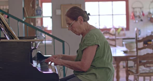 Old woman playing a grand piano at her home