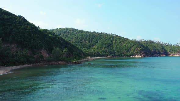 Beautiful secluded coast of tropical island with rocky slopes going down to seabed under calm clear