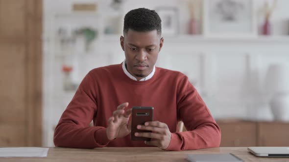 Attractive African Man using Smartphone in Office