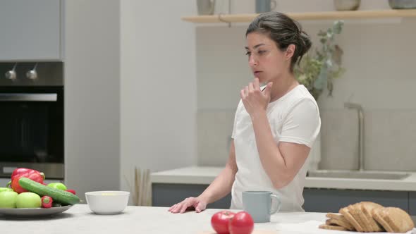 Young Indian Woman Thinking While Standing in Kitchen