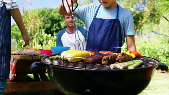 Kids grilling meat and vegetables on barbecue