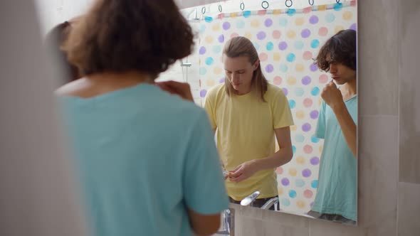 Happy Gay Couple Brushing Teeth in Bathroom Together