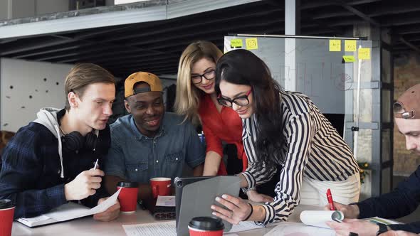 Creative Multi Ethnic Team Discussing a New Project Using Computer Device at a Meeting