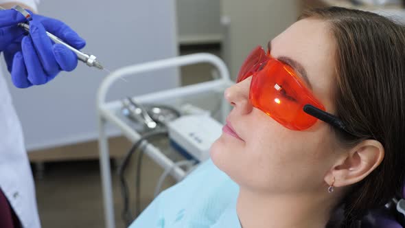 Portrait of Young Woman Afraid to Remove a Tooth Sitting in Dental Chair