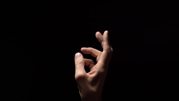 Slim Male Hand Reaching Out To Light on Black Background