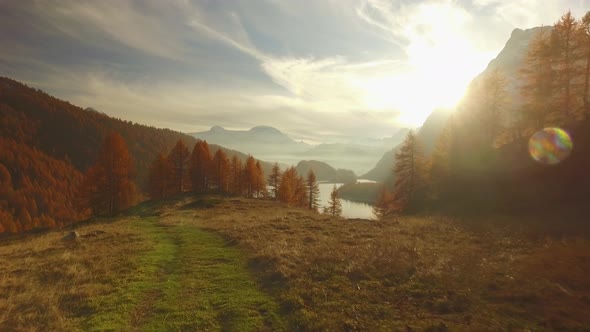 POV Walking on Fall Path to Woodsvalley Lake and Snowy Mounts at Sunset with Sun Flare