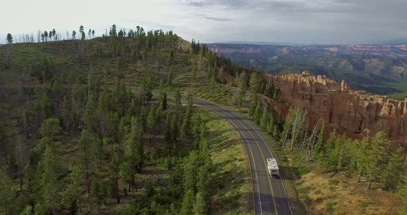 Drone camera circles over a white trailer driving along the gorge in Zion National Park, Utah, USA