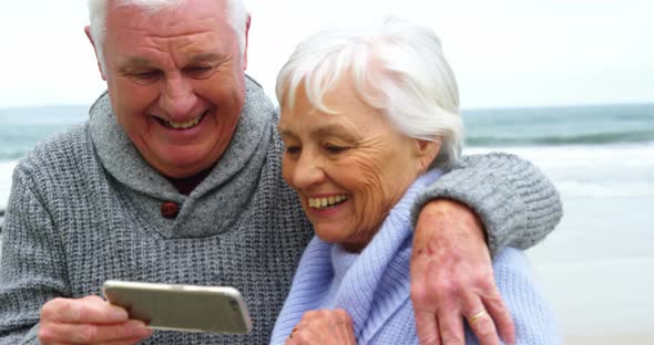 Senior couple checking photos on mobile phone