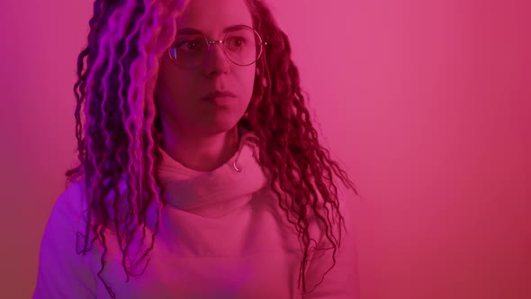 A Woman with Glasses Chews Gum on a Pink Studio Background in Neon Monochrome