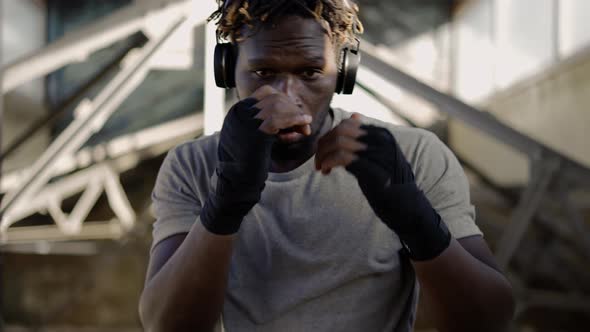 Afro American Young Male Boxer Practicing Shadow Boxing Around the Metal Structures Close Up