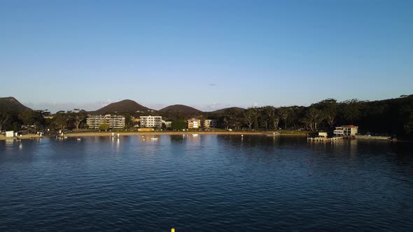 Fasting drone view over water looking back at a popular holiday spot in Nelson Bay Port Stephens Aus