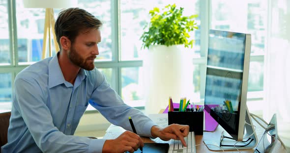 Male graphic designer working over graphic tablet at her desk