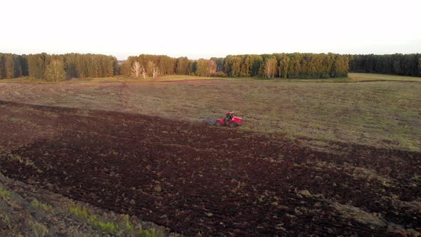 Red tractor, riding and plowing soil