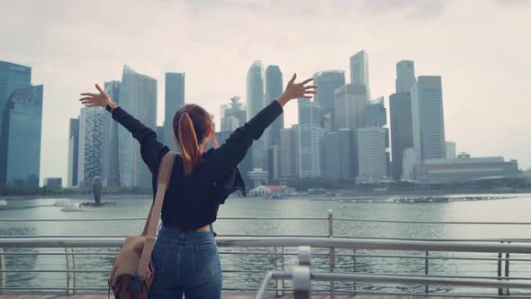 Tourist woman relaxing with her arms raised to her head enjoying looking view of Singapore city