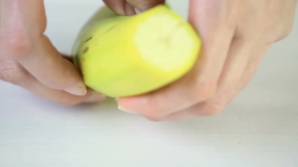 Slicing banana on a white cutting board.